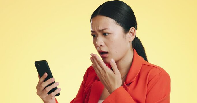 Asian woman, phone and shocked for bad news, loss or disbelief against a studio background. Female face in shock with facial expression on smartphone for terrible text, message or alert on mockup