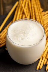 Thin and long bread sticks made of wheat flour and a glass of milk