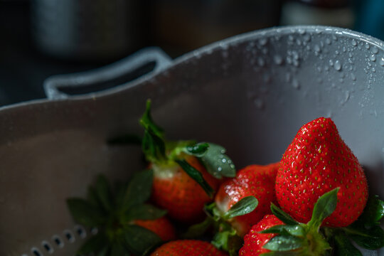 Freshly washed strawberries in a colander with drops of water
