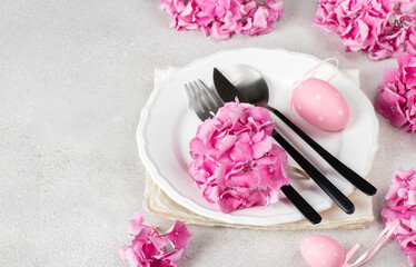 Obraz na płótnie Canvas Elegance Easter table setting with pink hydrangea flowers and eggs on gray background. Space for text