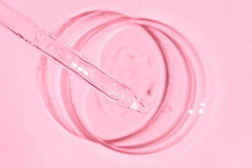 Petri dish. With transparent gel. The pipette lies. Cosmetic dispenser. On a pink background.