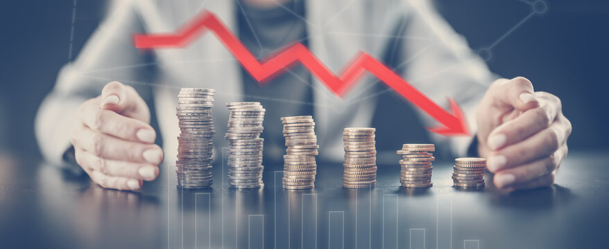 Woman sitting at the table and holding hands around the towers of the coins.