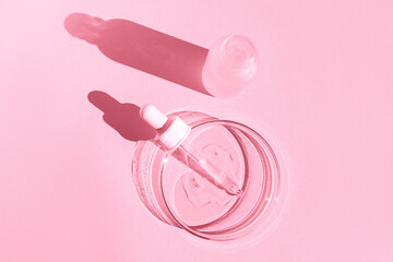 Petri dish. With transparent gel. With a pipette. Cosmetics bottle. On a pink background.