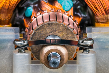 Closeup of commutator copper segments and plain bearing bronze housing in plastic pillow block. Steel flat leaf spring with screws inside old blender electric motor with rotor and stator wire winding. - obrazy, fototapety, plakaty