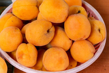Ripe fresh apricots in plastic bowls. Sale of apricots at the farmers' market. Close-up