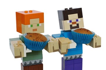 Obraz premium LEGO Minecraft large figures of Steve and Alex holding small baked muffins placed in blue paper cups. White backgound