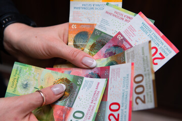 swiss francs in different denominations held in female hands