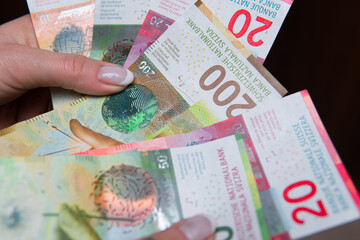 close-up of CHF swiss francs in different denominations held in woman's hands. Swiss economy, banking and finance