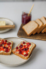 Bread with butter and cranberry jam is on the table and ready to eat. A delicious and sweet breakfast. Aesthetically pleasing serving of food. Recipe for toast with butter and jam.