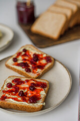 Bread with butter and cranberry jam is on the table and ready to eat. A delicious and sweet breakfast. Aesthetically pleasing serving of food. Recipe for toast with butter and jam.