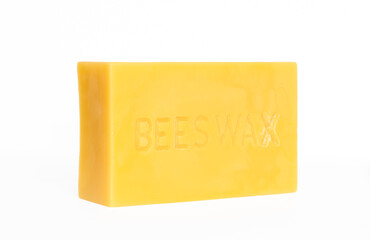 An angled view of a brick of pure beeswax on a white background