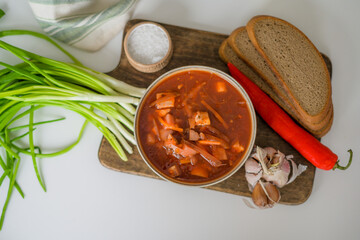The traditional Ukrainian first course is red borsch. Hot borsch on the table with garlic, pepper, salt, onions and Ukrainian rye bread. Recipe for borsch with vegetables