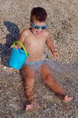 A portrait of a cute little boy who laughs on a warm summer day. Concept of summer holidays at sea and live style - 582296959