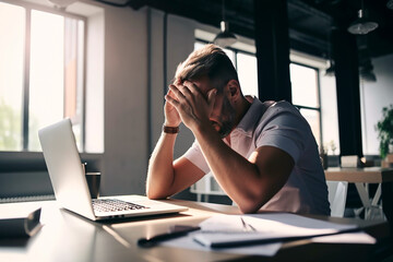 Businessman sits at a table with his head in his hands. Negative emotions due to problems on his work. Creative Ai