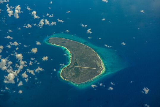 Aerial landscape view of isolated Assomption Island, Seychelles, located in the most southwestern part of Seychelles, part of Aldabra Group, with Assomption Airport and its runway crossing the Island