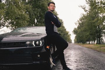 sexy man and black sports car. Handsome guy traveling by his car.  Sportive man. guys love toys