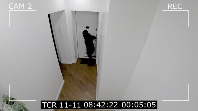 a masked thief enters the apartment. Surveillance camera for a burglar breaking into a house.