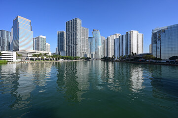 Fototapeta na wymiar Residential and office towers in downtown Miami, Florida reflected in calm water of Biscayne Bay on sunny clear morning.