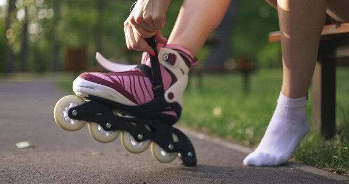 Girl carefully fastens rollerblade on her foot