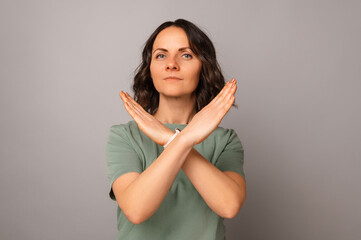 Obraz premium Studio shot of a confident mid age woman is crossing hands for a stop gesture.