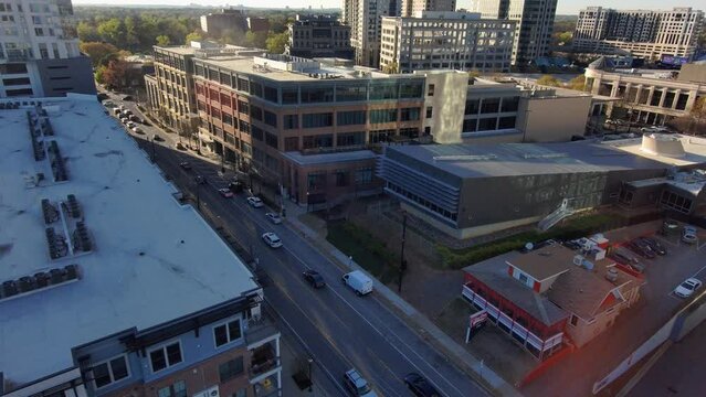 tilt aerial footage of skyscrapers and office buildings in the city skyline in Buckhead at sunset with cars driving on the street and a gorgeous clear blue sky in Atlanta Georgia USA