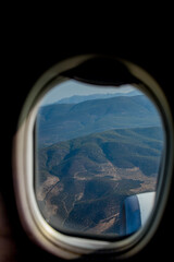 View of the mountains from the plane window. View from a height. Earth and sky through the airplane window.