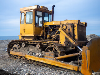 Obraz premium Bulldozer for excavation. Tractor from the Chelyabinsk Tractor Plant. Part of an orange tractor. Soil of pebbles and earth