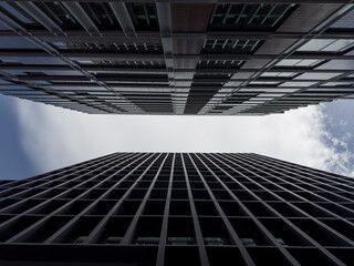 Symmetrical view up of two skyscrapers in urban area