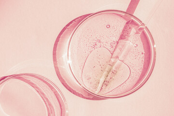 Petri dish. Petri's cup with liquid. Chemical elements, oil, cosmetics. Gel, water, molecules, viruses. Close-up. On a pink background.