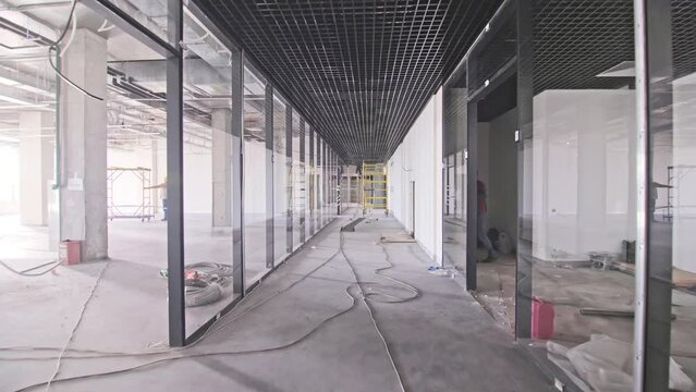 Long empty corridor with scaffolds in future business center. Construction site of contemporary public building