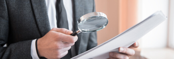 man holding magnifier and document