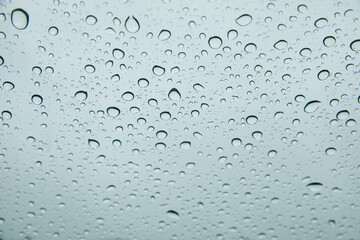 Round blue drops of water in the middle of a rain on a window