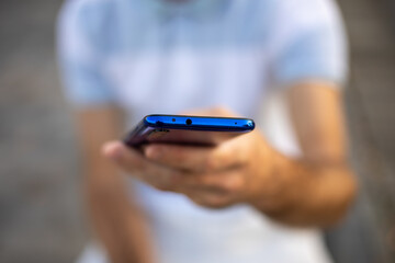 Closeup shot of an young modern man holding mobile phone in hand, blurred background
