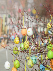Top view of twigs with decorative Easter eggs on blurred background