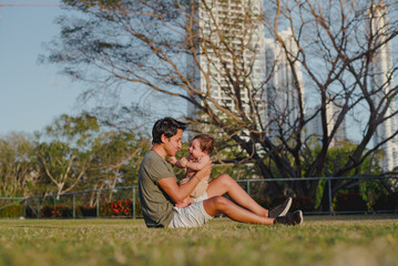"City park bonding: millennial father kissing smiling baby on lawn"

