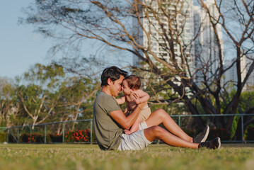 "Tender parenting moment: dad cuddling baby boy with skyscrapers in background"

