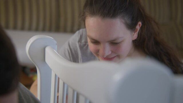 Face close up view of caring woman helping man with assembling crib for future baby at nursery. Loving couple together preparing room for adorable infant. Concept of parenthood, childhood and family.