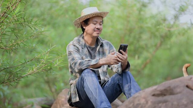 Asian man working on smartphone in the forest.