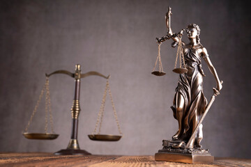 Law and justice concept. War crimes. Gavel, scale and Themis sculpture in lawyers office. Gray background.