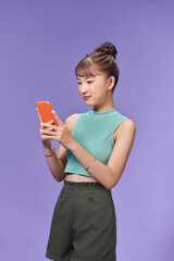 Pretty millennial girl isolated on purple background text messaging on cell phone