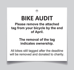 Bike audit tag on grey background with shadow. Bicycle amenity audit tag with detailed instructions. Used by strata and building management to find unclaimed and forgotten bikes. Selective focus. 