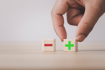 Wooden blocks showing plus and minus signs. The concept of antithesis. Decision making. Positive or...