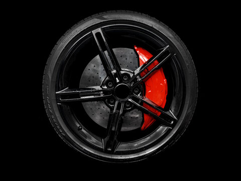 Car alloy wheel and tyre isolated on black background. New alloy wheel with tire and red carbon ceramic brakes. Alloy rim isolated. Car wheel disc. Car spare parts.