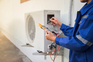 Air conditioning, HVAC service technician using gauges to check refrigerant and add refrigerant.	