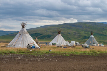Three wigwams of modern reindeer herders against the background of the foothills of the Polar Urals on a cloudy August day. Yamalo-Nenets Autonomous Okrug, Russia © sikaraha