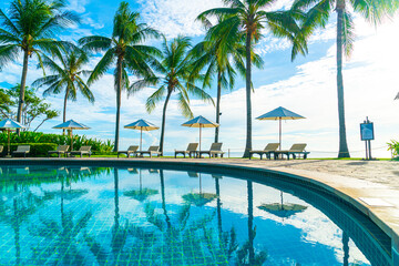 Beautiful luxury umbrella and chair around outdoor swimming pool in hotel and resort with coconut...