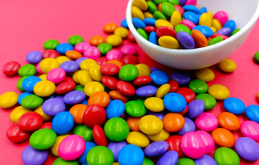 Colorful candies in bowl on pink background. 