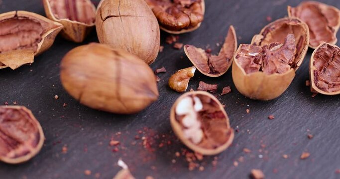 dry mature pecan on a slate board, broken shell dry pecan nuts scattered on a slate stone