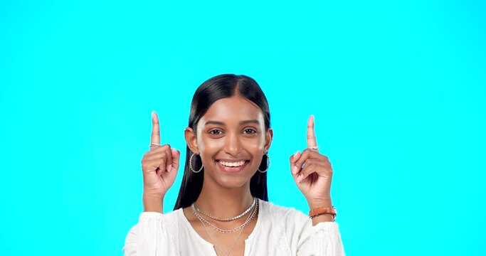 Mockup, face and Indian woman pointing up, promotion and success on a blue studio background. Portrait, female and lady with gesture for motivation, inspiration and carefree with decision and choice