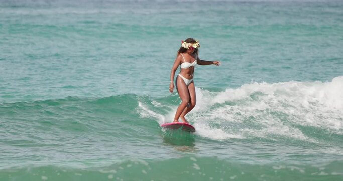 Young African-American woman surfing on the longboard in Hawaii in the ocean